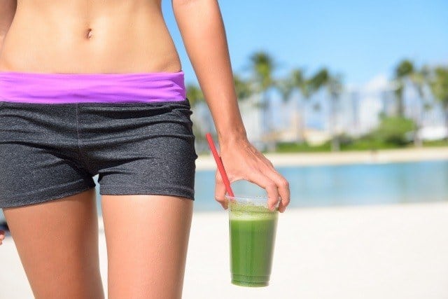 woman on beach with green smoothie