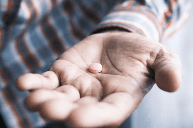 pink pill on an elderly's palm
